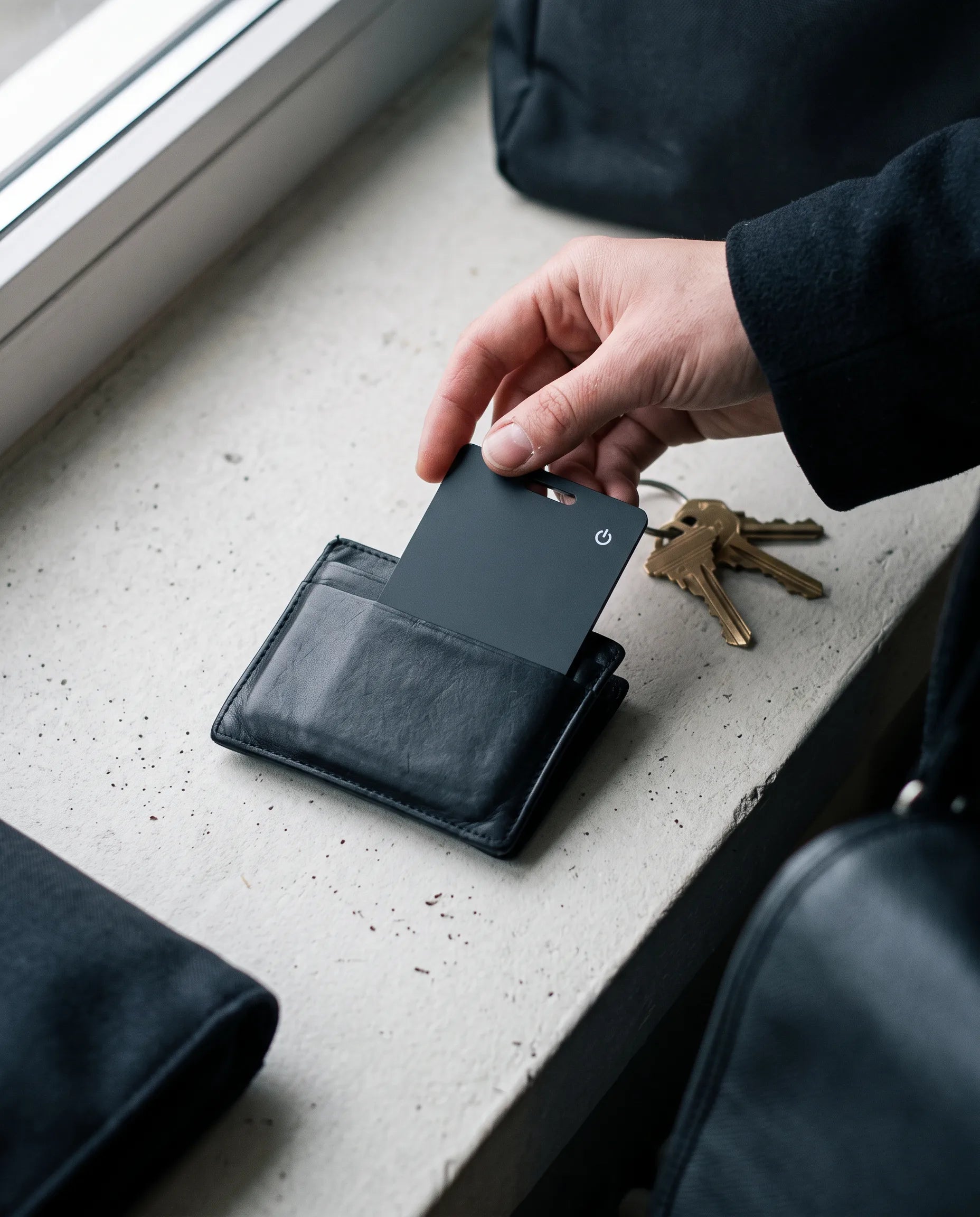 Tracking card sliding into a black leather wallet on a concrete shelf